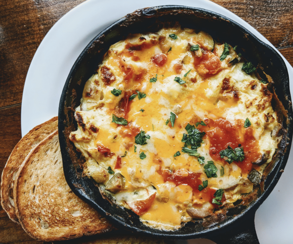 omelette in a skillet with ham and tomato