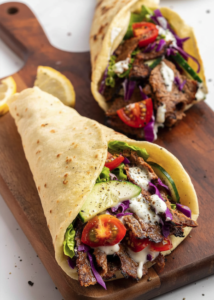 lamb doner wrap on a wooden board filled with salad