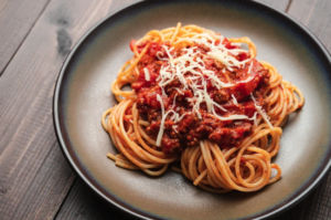 beef mince spaghetti bolognese served onto a plate with cheese
